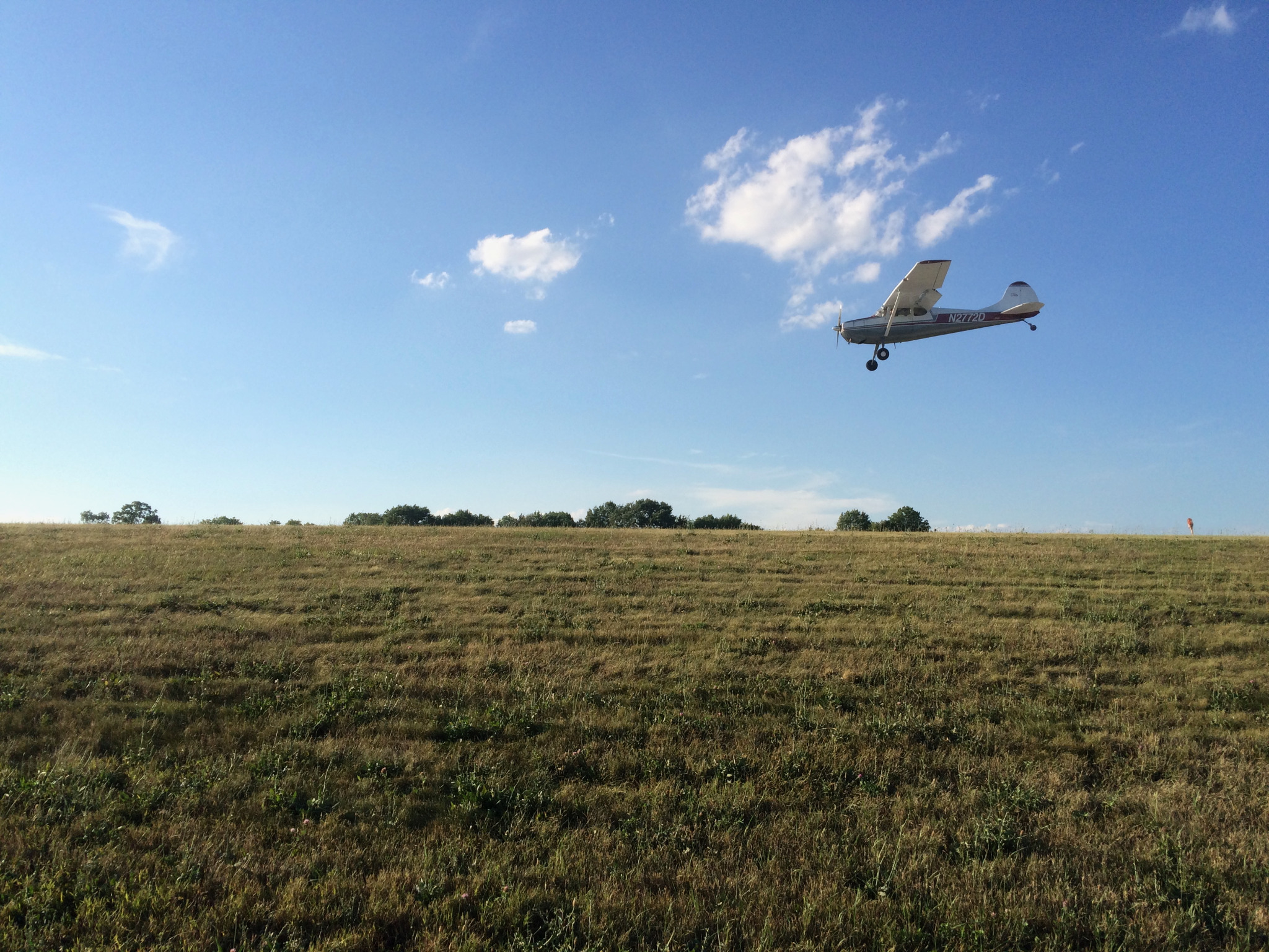 Small airplane approaching over an open field